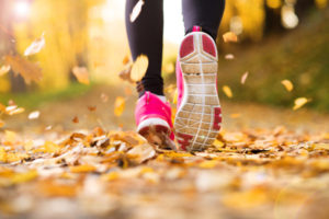 Close up of runner’s feet running in autumn leaves training exercise